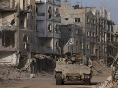 Sebuah kendaraan lapis baja melaju sementara bangunan-bangunan yang rusak terlihat di latar belakang, di tengah operasi darat yang sedang berlangsung oleh tentara Israel melawan kelompok Islamis Palestina, Hamas, di Jalur Gaza, 13 September 2024. REUTERS/Amir Cohen